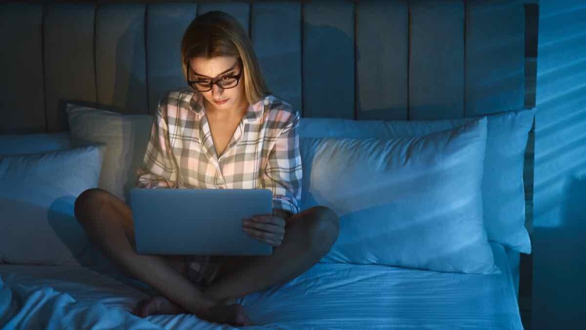 Woman uses laptop in bed